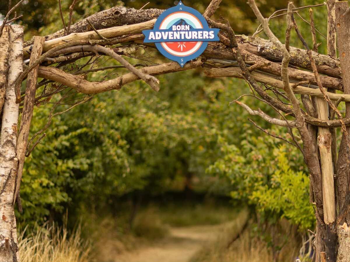 A hand-built timber archway marking the entrance to a woodland path